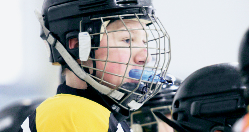 Young boy playing hockey protects his teeth by using a sports mouthguard